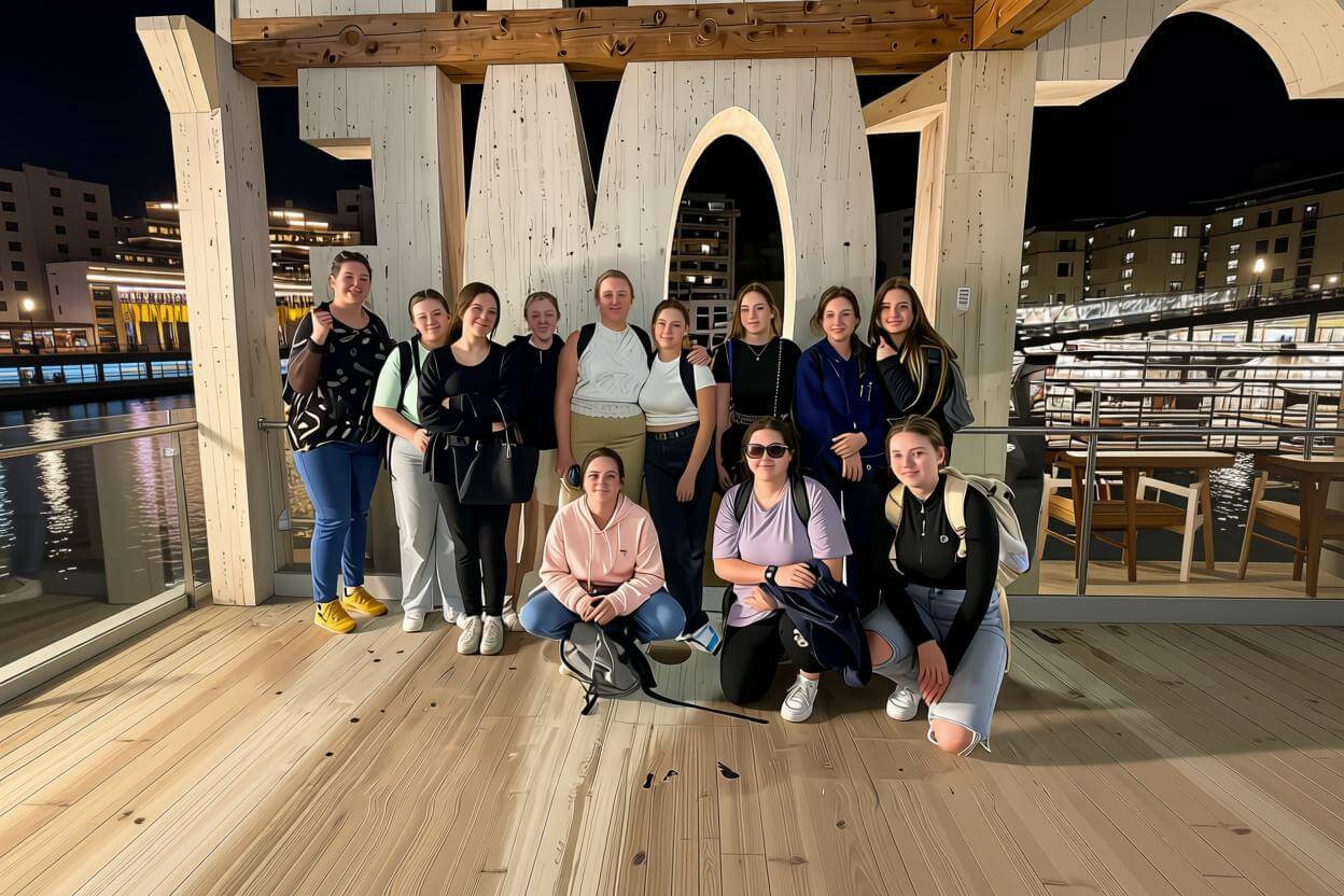 Students group photo at indoor venue with wooden archway